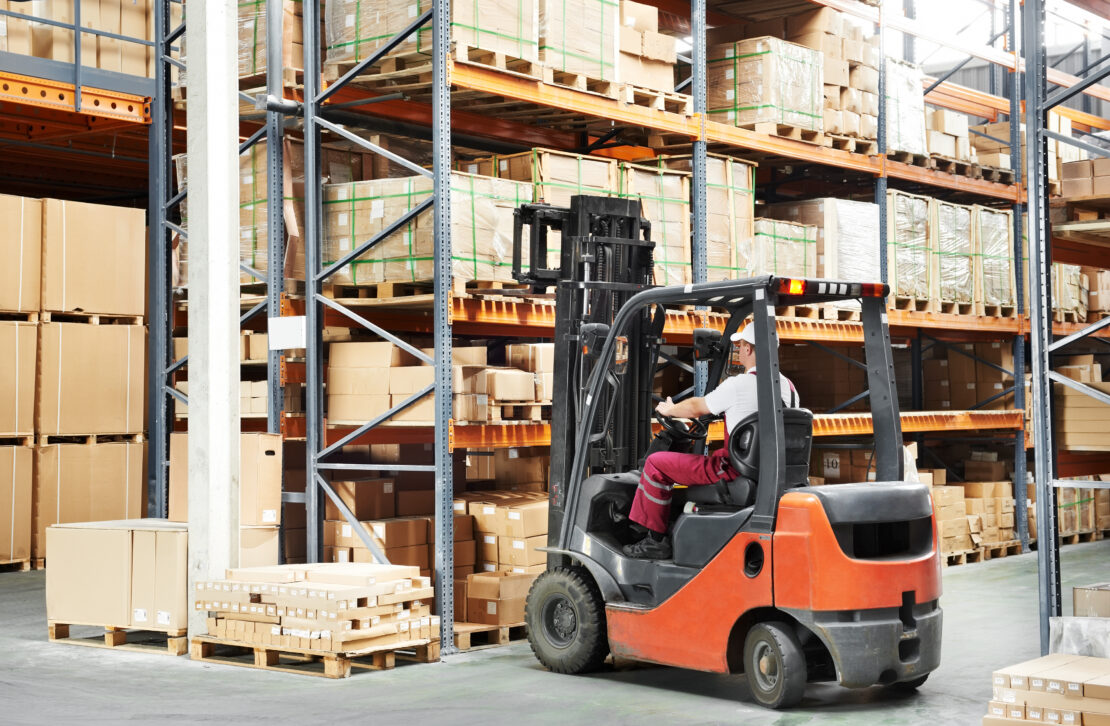 Warehouse worker moving shipping boxes with forklift